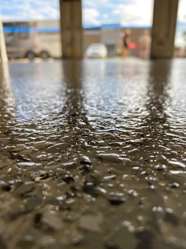 Close-up of a dark charcoal flake concrete coating on a garage floor